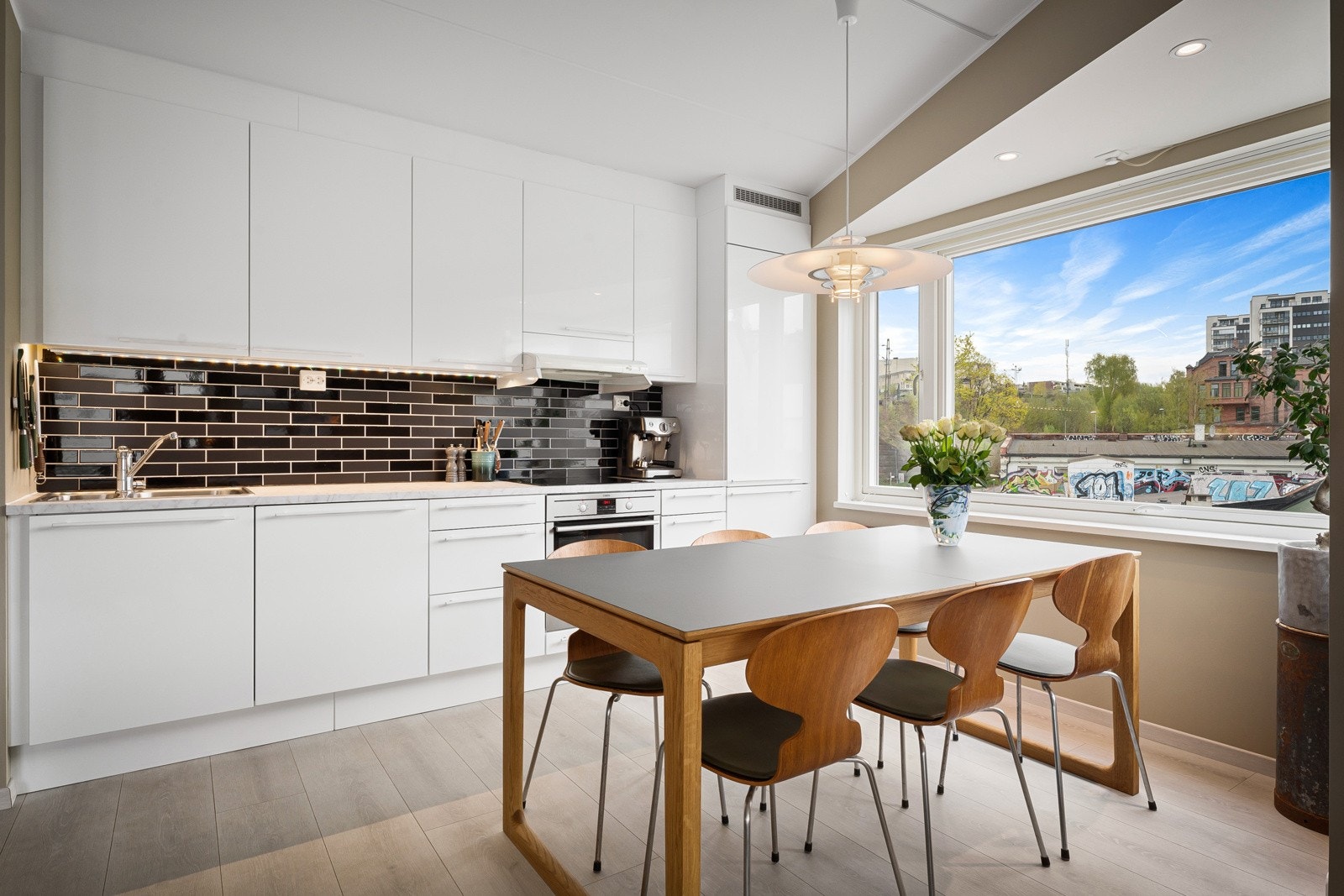 Kjøkkeninnredningen strekker seg langs én vegg i rommet og har et stilrent design som understreker leilighetens moderne kvaliteter. Innredningen har takoppforede skap, hvite høyglansfronter, benkebelysning og avtrekk fra ventilator. Galleribilde