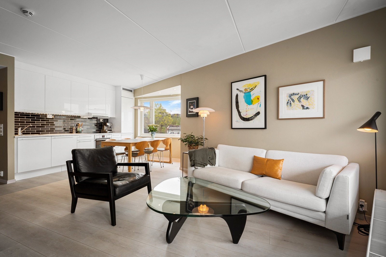 Veggene er malt i en varm beigefarge med en mørk blå kontrastvegg som strekker seg fra entreen og inn i stuen. I himling, som har en takhøyde på inntil 2,47 meter, er det montert to høyttalere. Galleribilde