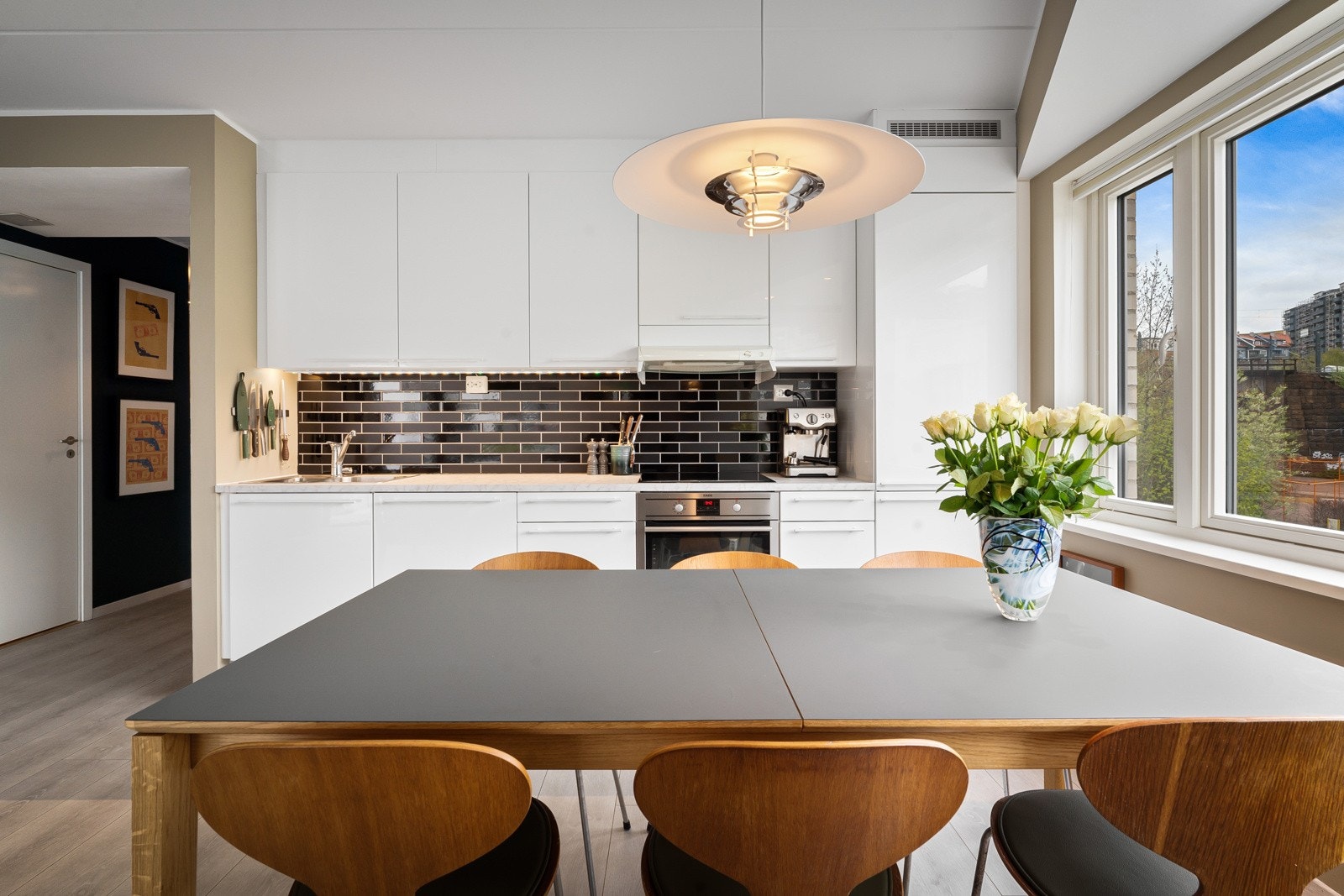 Øvrige hvitevarer som stekeovn, oppvaskmaskin og kjøl/frys er integrert. På veggen over benken er det sorte, glansfulle veggfliser og ved kjøkkenvinduet er det nedforet himling med to nye downlights. Galleribilde