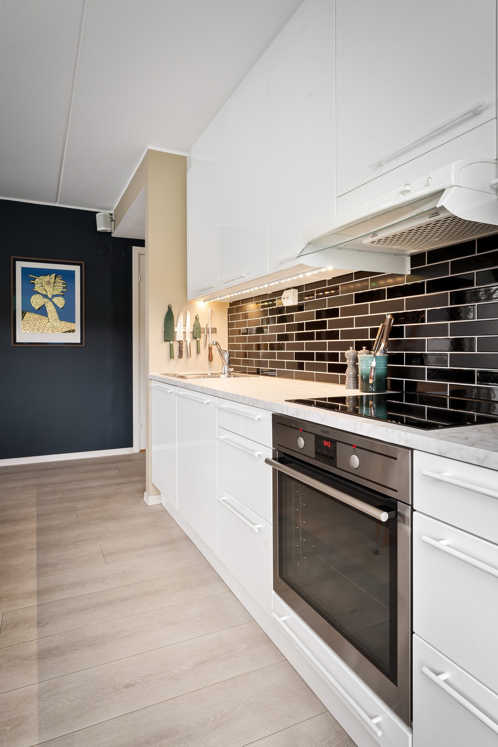 I laminert benkeplate med marmormønster er det nedfelt, dobbel oppvaskkum i stål og induksjonstopp. Galleribilde