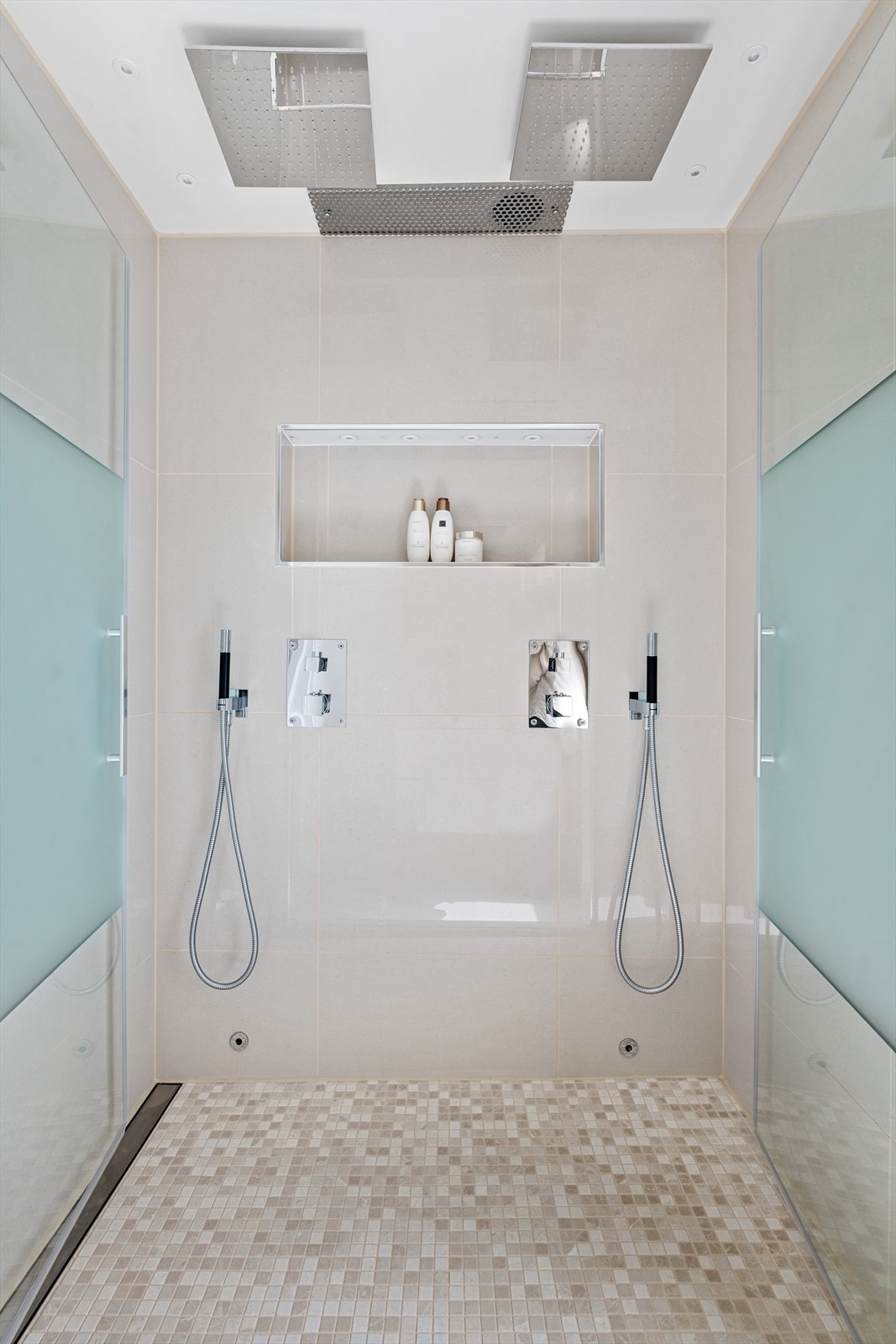 Stor dusjnisjé med dobbel takdusj og lekre glassdører. Badet er påkostet eksklusive detaljer som linjesluk og blandebatterier fra Tapwell med åpen fossekran Galleribilde