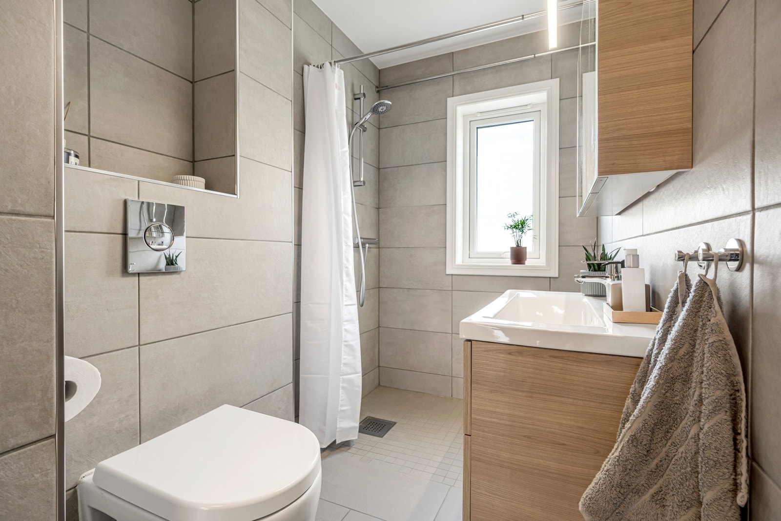 Særdeles flott bad med flislagte flater og varmekabler i gulv. Her er det valgt arealeffektive løsninger som gjør at man har et bad som oppleves romslig og luksuriøst. Galleribilde