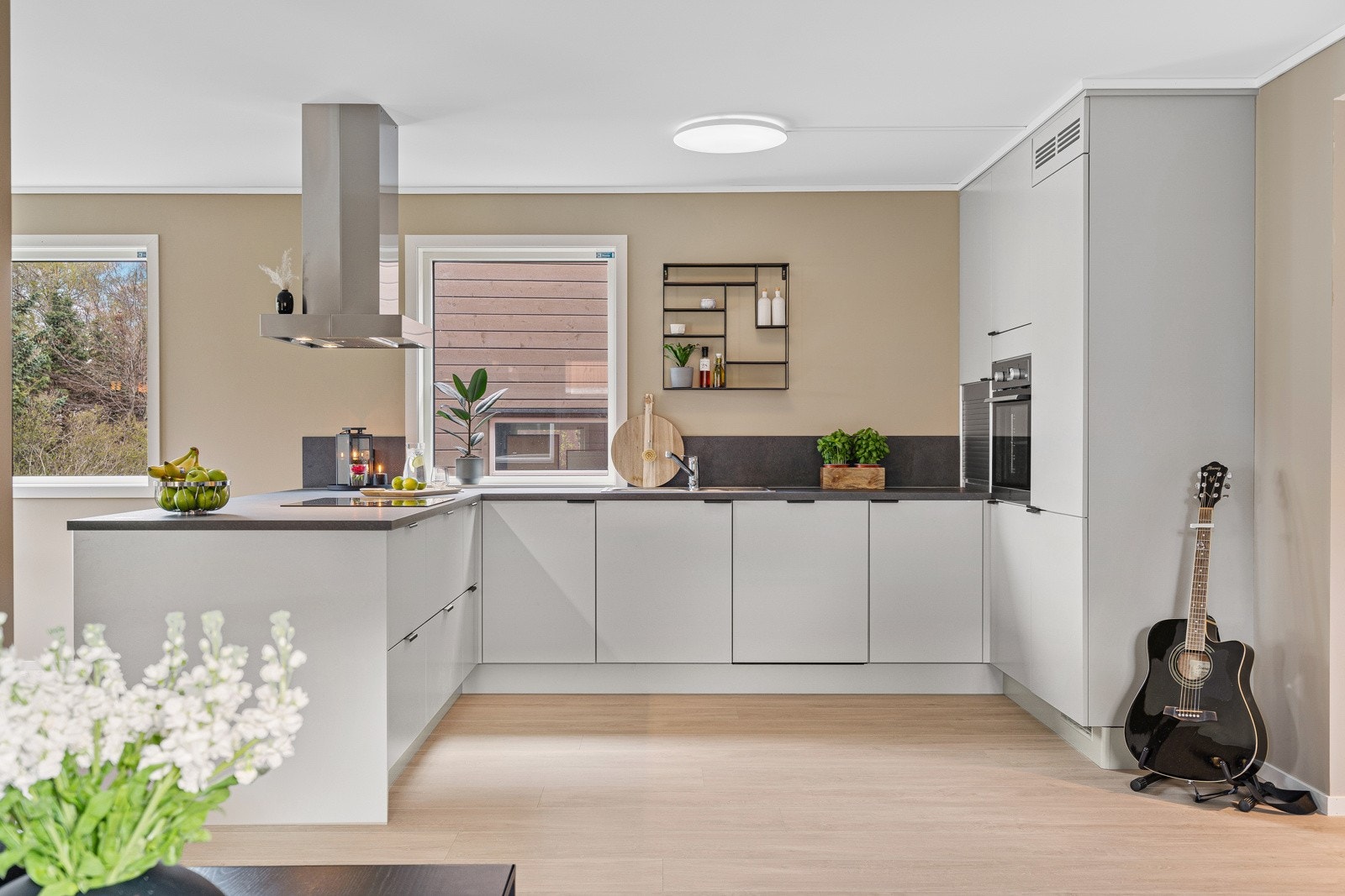 Lekkert kjøkken i praktisk utforming for ekstra god skap- og benkeplass Galleribilde