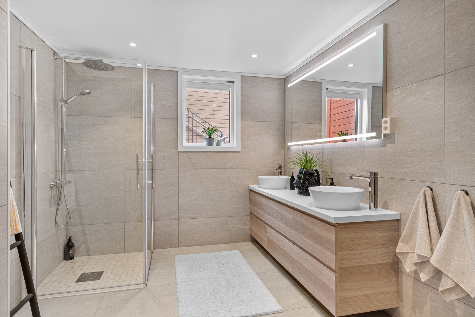 Badet er utstyrt med varmekabler i gulv, downlights i himling, dobbeltservant, vegghengt wc og dusjnisje Galleribilde