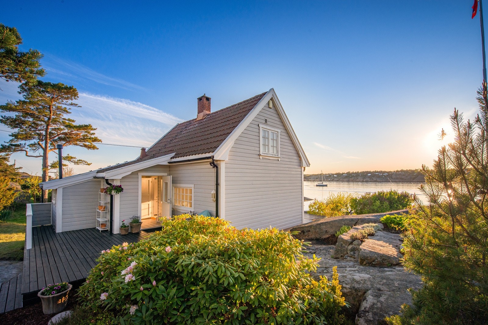 Hytta ble bygd i 1924 og er sjarmerende med lysmalt kledning, nydelige blomsterbed og prydbusker Galleribilde