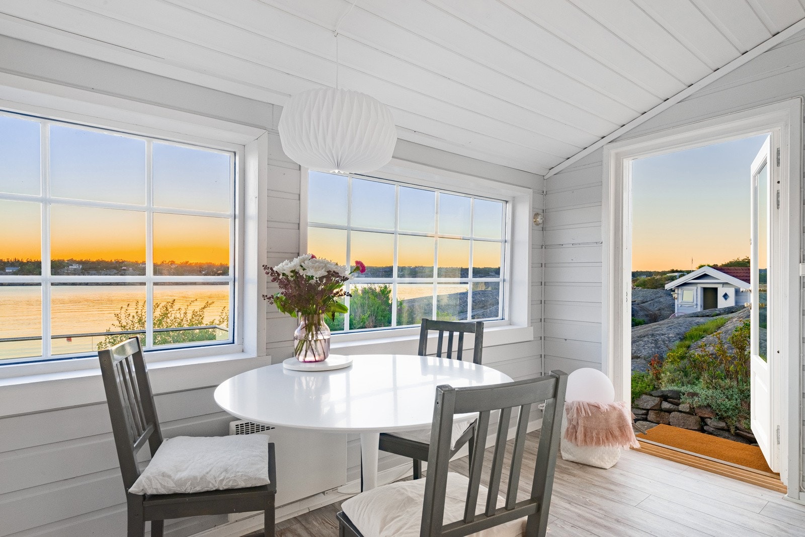 Herfra er det utgang til en vestvendt terrasse og hage med svaberg og bugnende beplantning Galleribilde