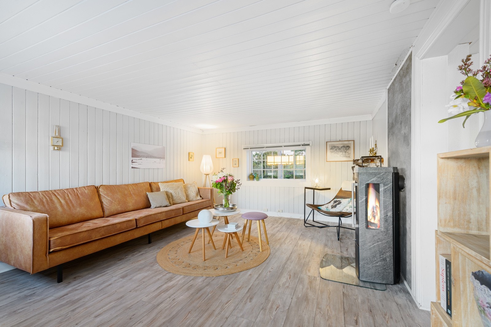 Koselig og lun stue med moderne peisovn fra 2017. Ovnen er kledd i kleberstein og har stort flammebilde Galleribilde