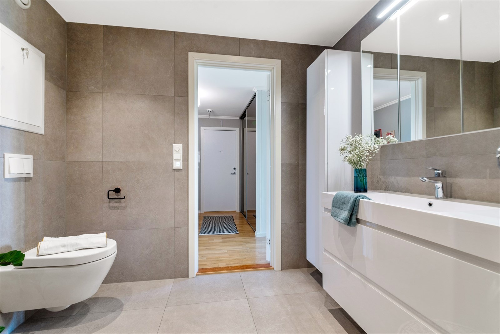 På baderommet er det dusjhjørne, vegghengt toalett, servant med skuffeseksjon, høyskap samt nisje med opplegg for vaskesøyle. Vaskemaskin/tørketrommel medfølger boligen. Galleribilde