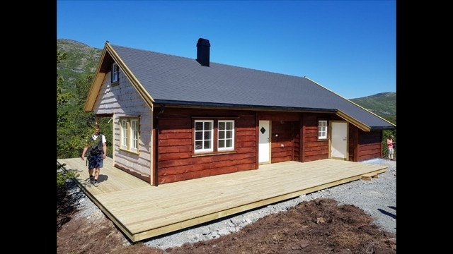 Berakupen med villmarkskledning og shingeltak. Utvida terrasse rundt hytta Galleribilde