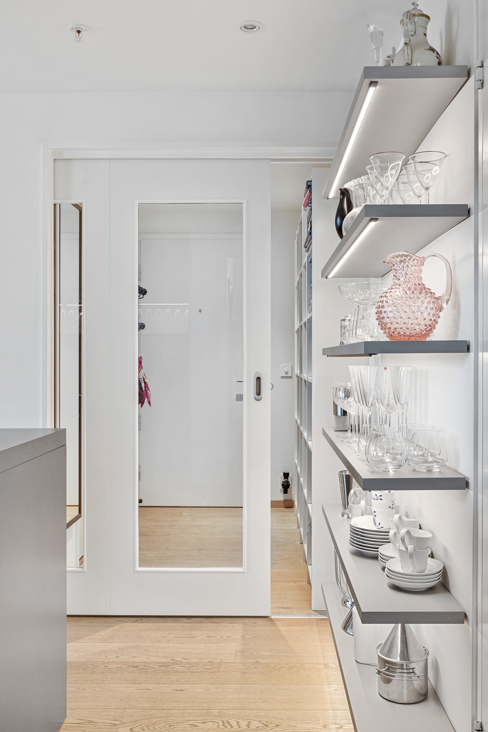 Det er glass-skyvedør mellom entréen og kjøkkensonen. Galleribilde