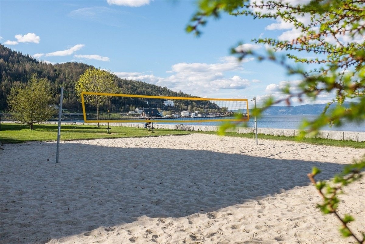Store grøntarealer langs strandpromenaden, med bla. sandvolleyballbane, lekeplass, bademuligheter og rolig plenområde Galleribilde