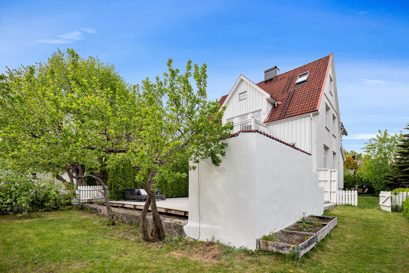 Terrassen skjermes med hvitmalte murvegger og høyreist hekk. Galleribilde