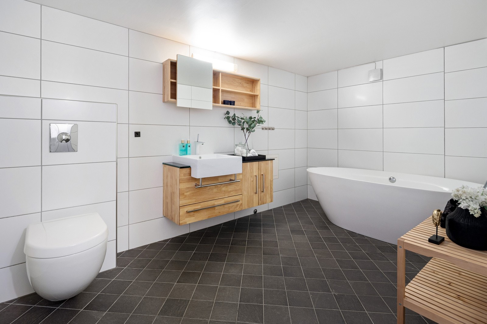 Det andre badet ligger i underetasjen og har adkomst fra hallen. Badet har samme type fliser som badet i første etasje og det er varme i gulvet. Badet har vegghengt toalett og et frittstående designbadekar med dusjmuligheter. Galleribilde