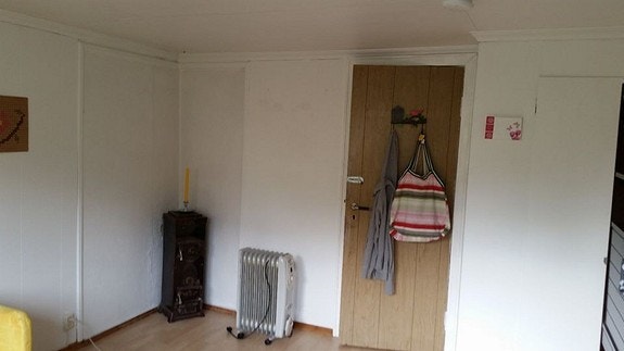 Hybel2. Ser stuen fra sør vest forran vinduene, mot døren nord øst som går til gangen. Badet er til høyre i gangen. Peisen til venstre i hjørnet. Galleribilde