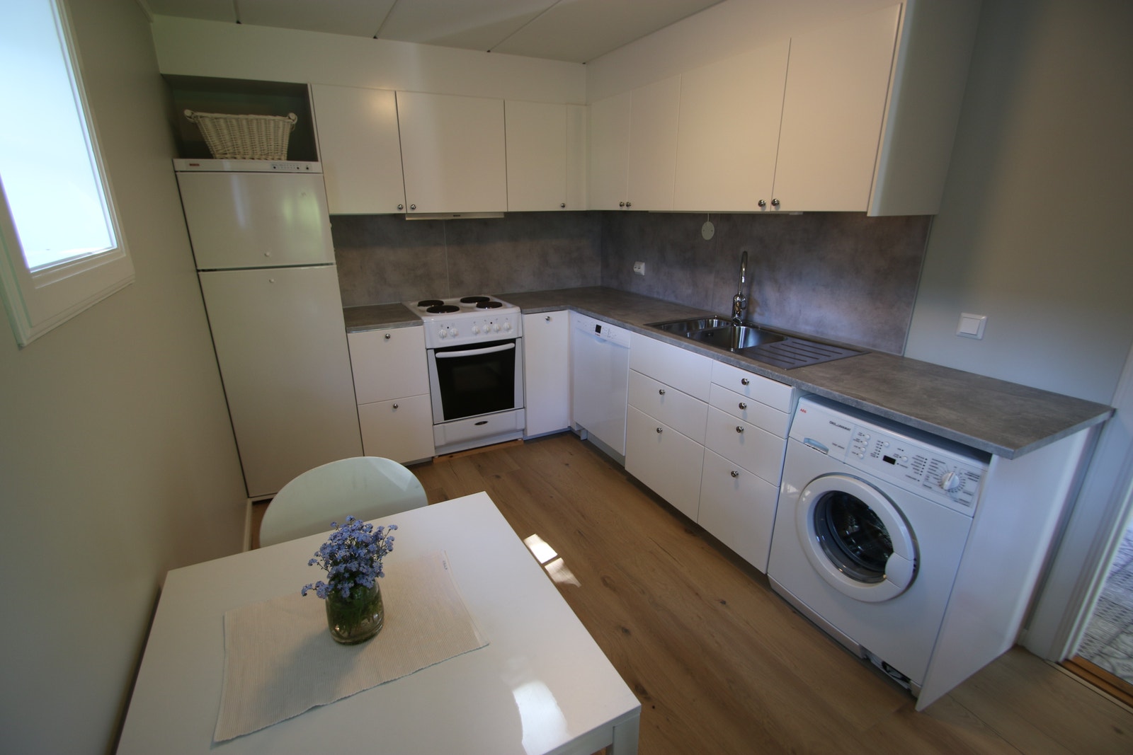 Stort kjøkken med spiseplass, oppvaskmaskin og vaskemaskin Galleribilde