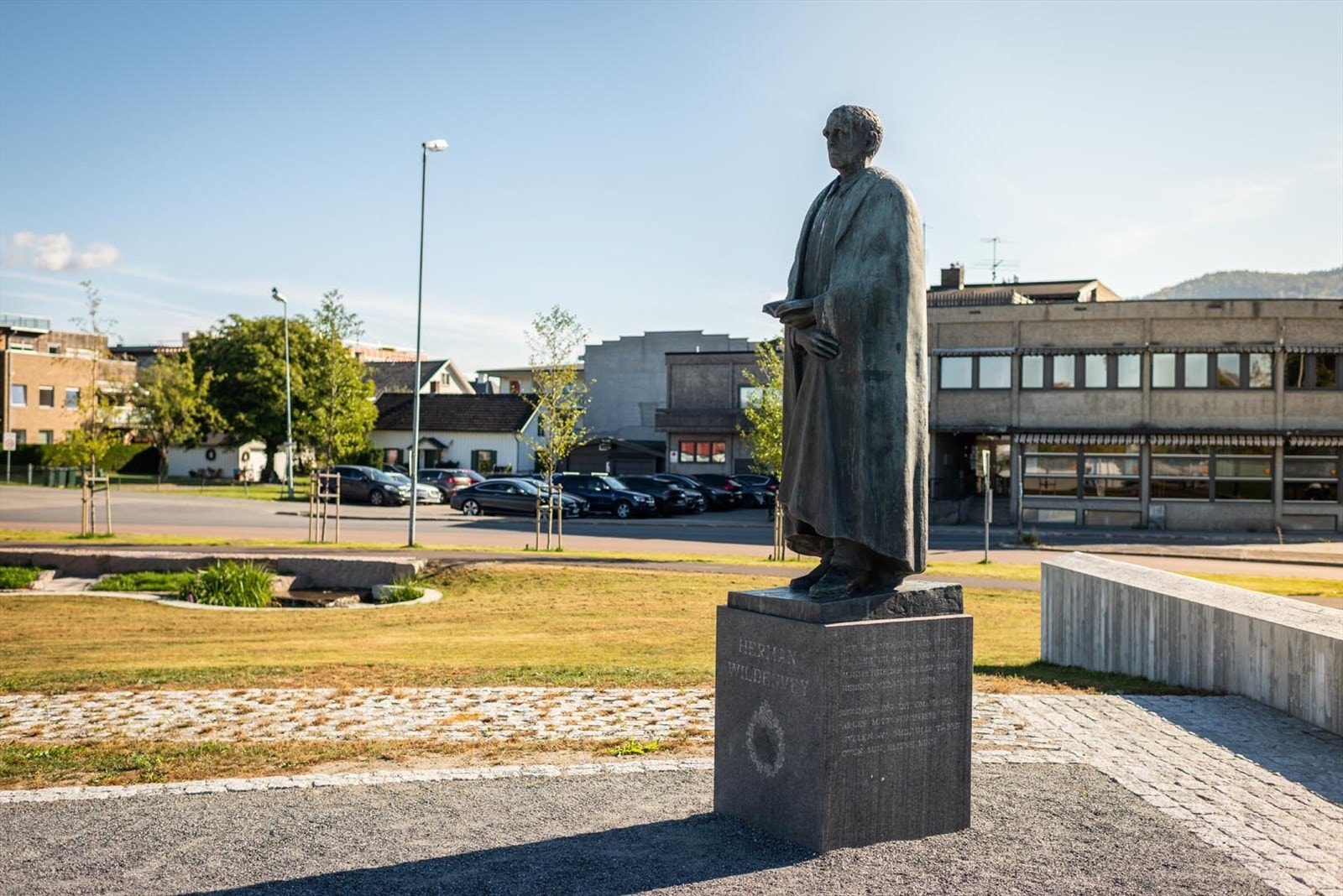Wildenveys plass med Herman Wildenvey på sokkel. Park med vannspeil, terrengtrapper, sitteplasser og kunst. Galleribilde