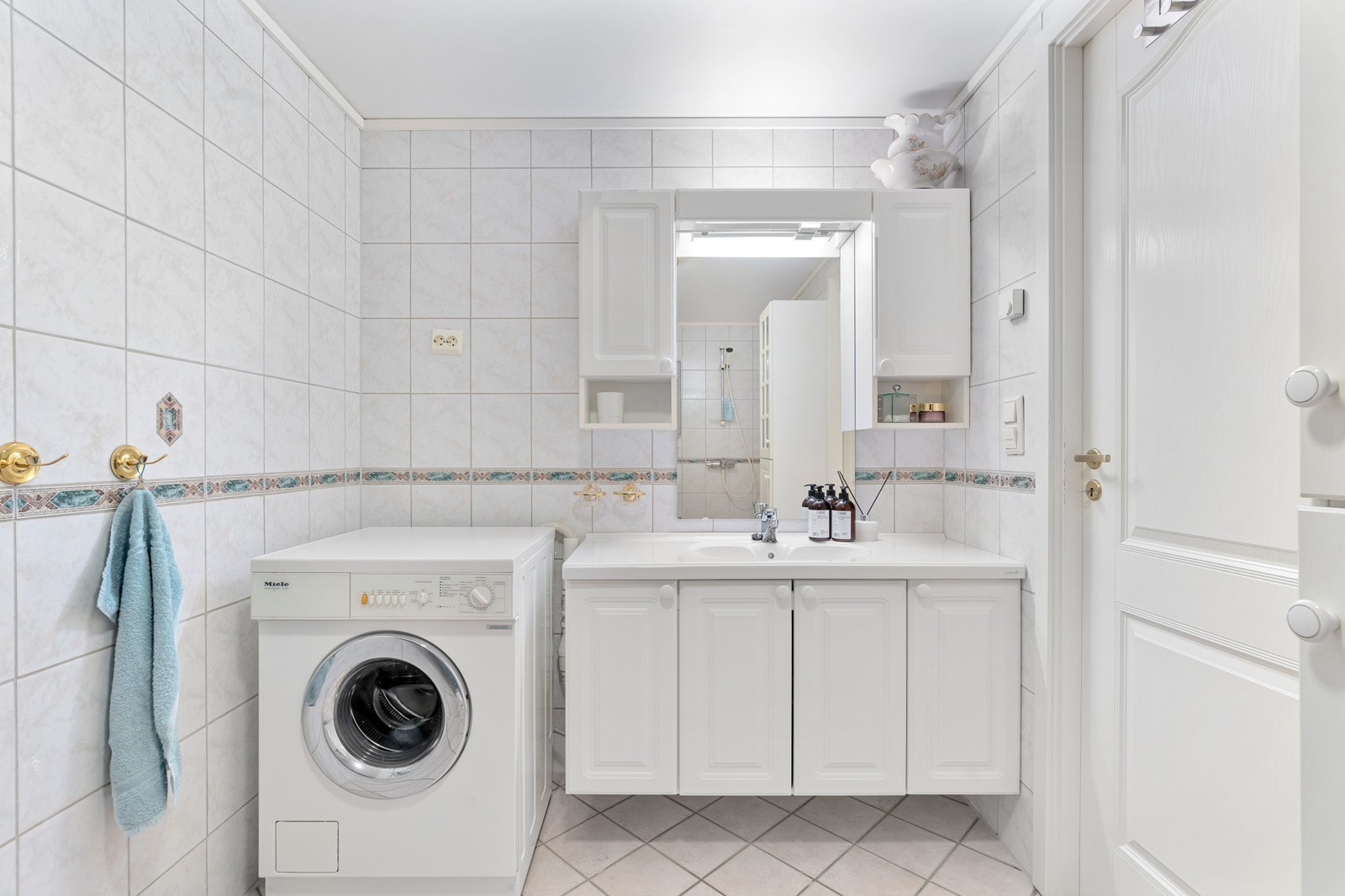 Badet er flislagt og utstyrt med dusjhjørne, gulvmontert wc og opplegg for vaskemaskin.