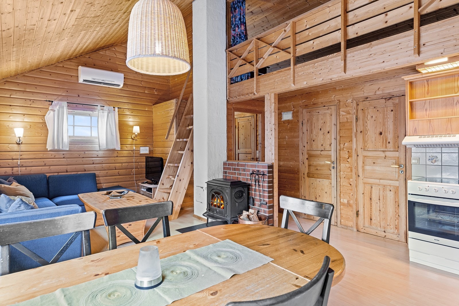 Stue og kjøkken i åpen løsning. Panel på vegger og trektak. Furugulv. Galleribilde