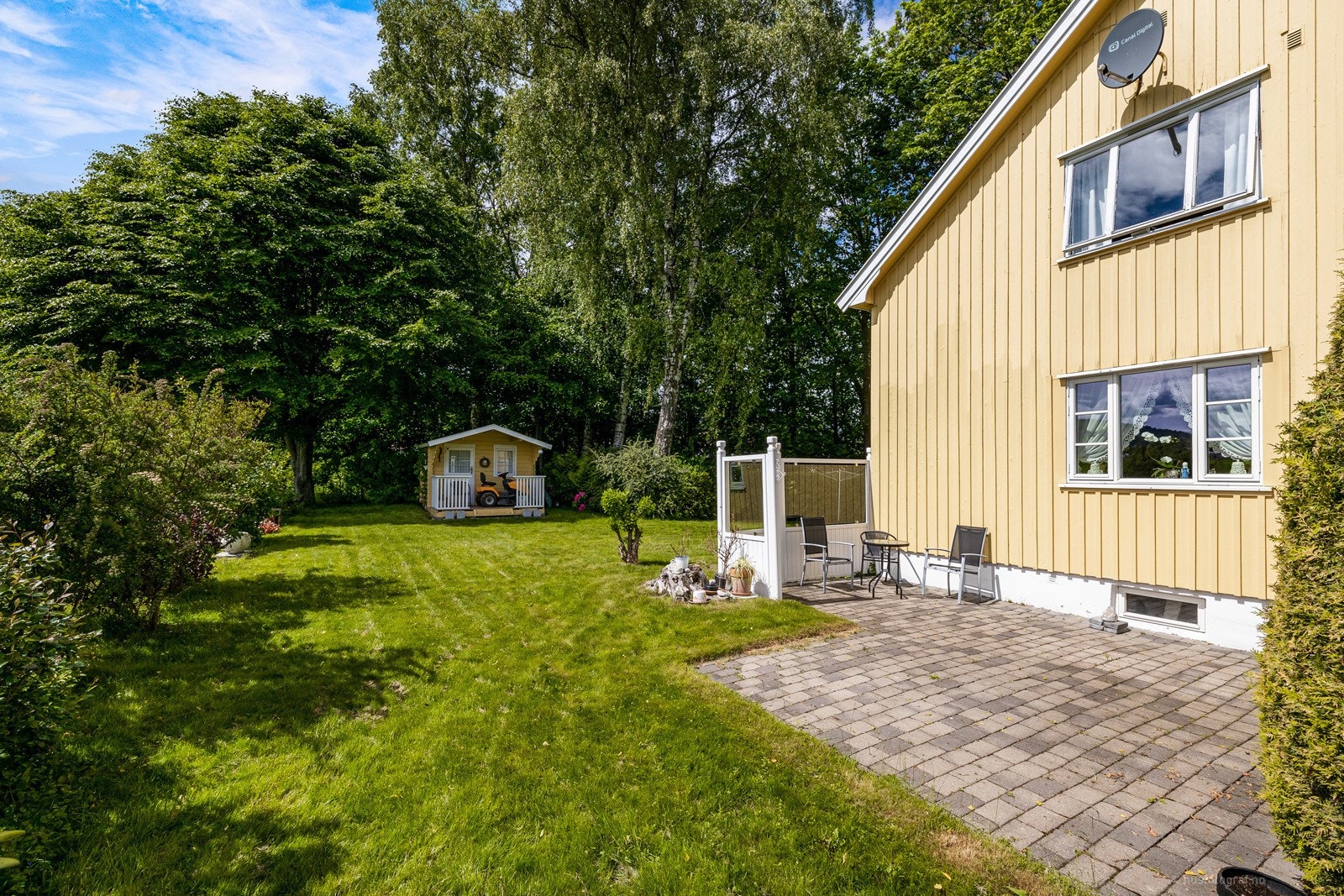 Beleggningsstein i forbindelse med terrassert areal. Tomten er pent opparbeidet med gressplen og beplantninger Galleribilde