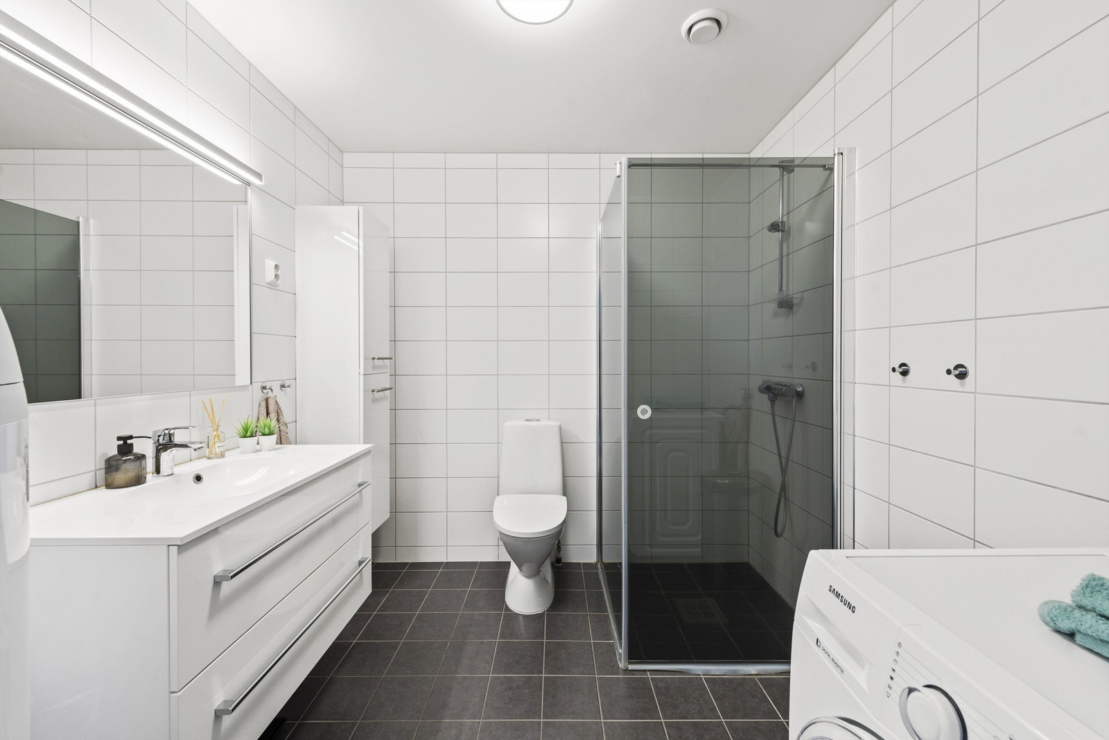 Pent flislagt bad med varmekabler og opplegg for vaskemaskin og tørketrommel Galleribilde