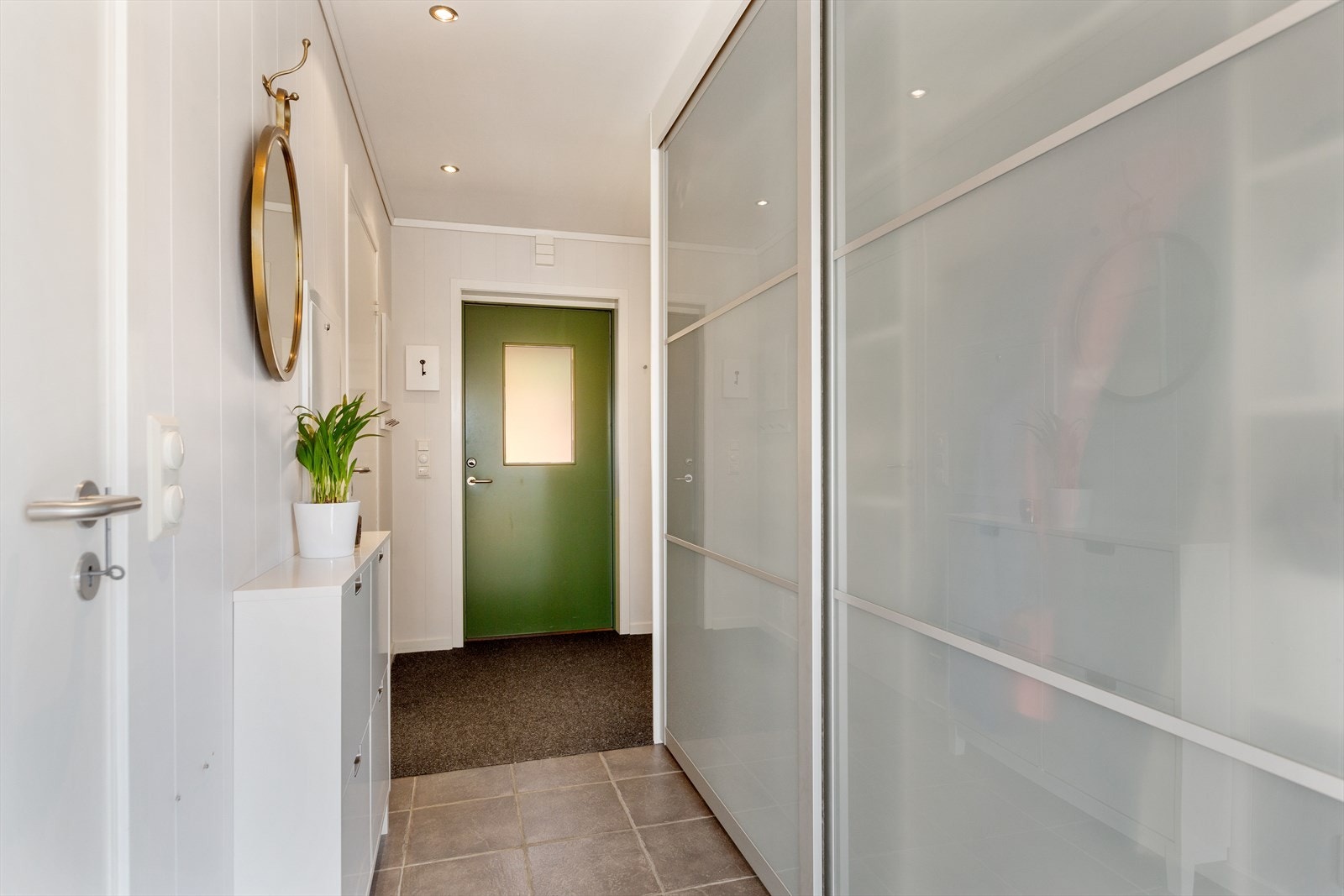 Du kommer inn i en luftig entré/hall med praktisk skyvedørsgarderobe for oppbevaring. Galleribilde