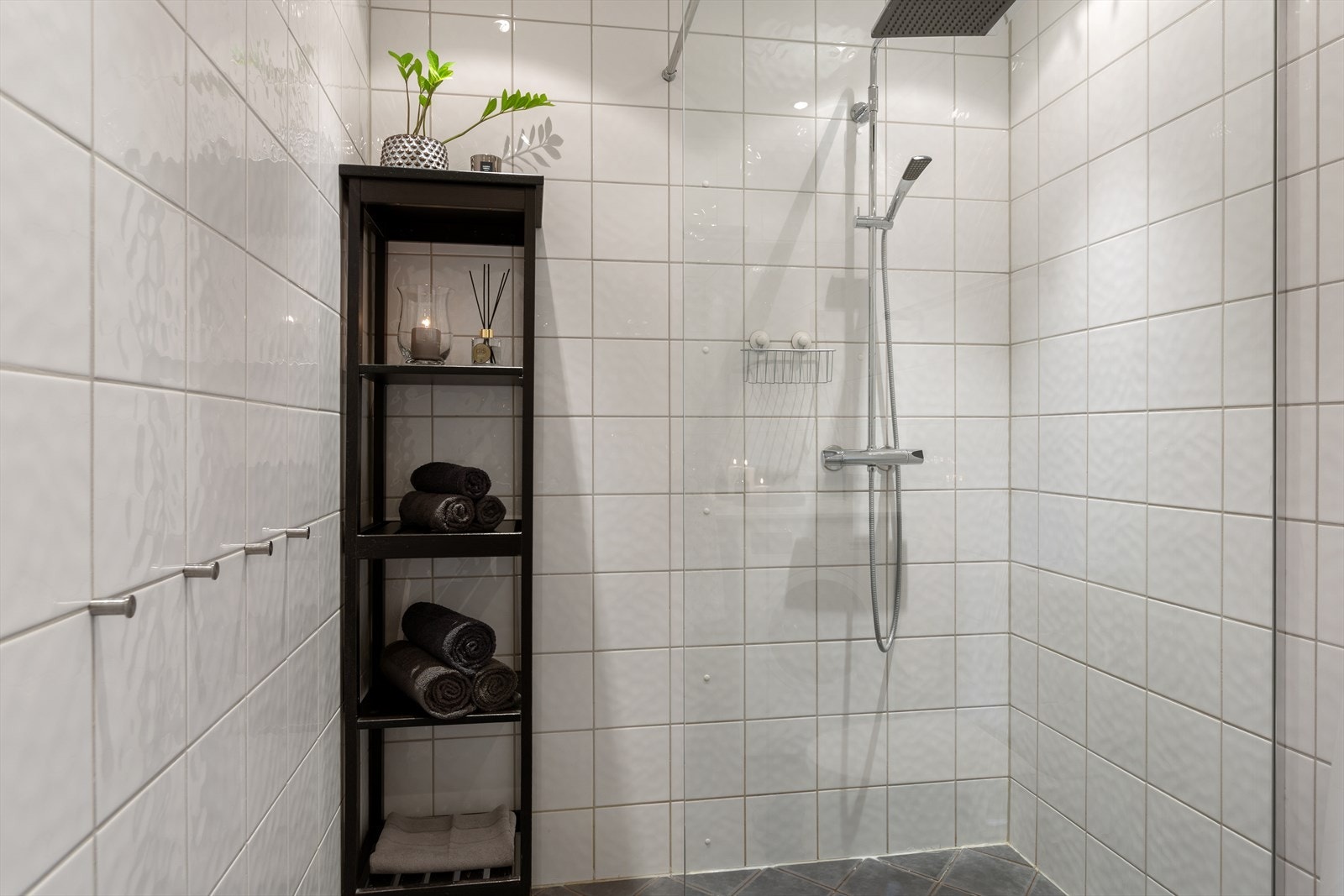 Sanitærutstyr bestående av dusjnisje med glassdør, servant og gulvmontert toalett. Galleribilde