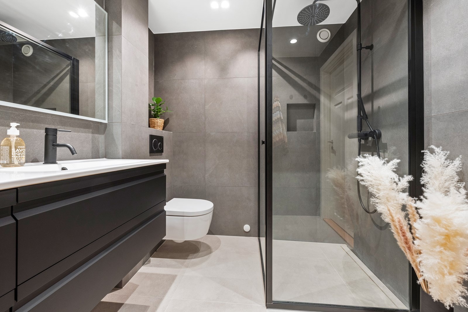 Baderommet fremstår meget delikat med flislagte overflater, mørk innredning med dobbel servant, speil med integrert belysning og stor dusjplass med rainshower. Galleribilde