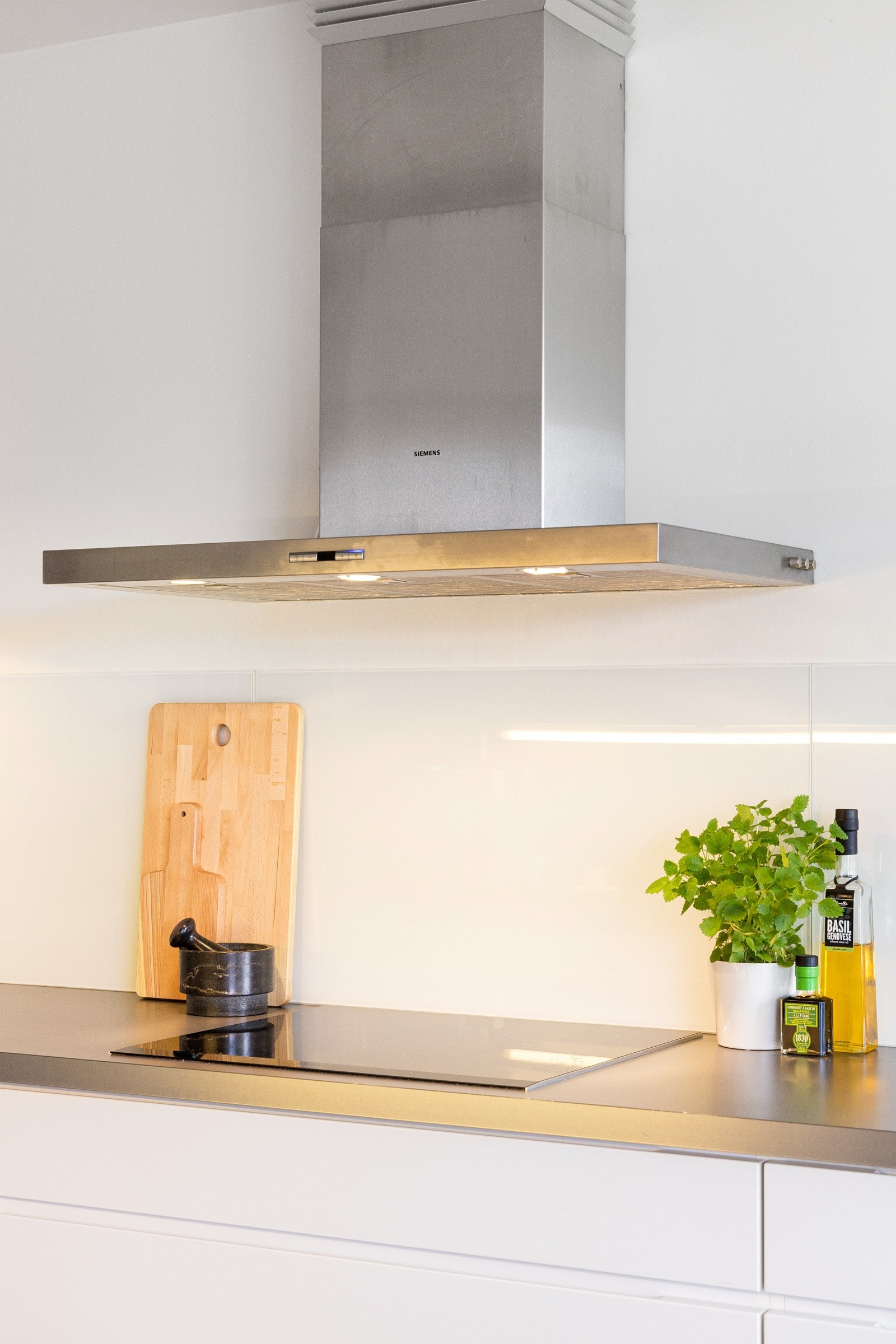 Det er montert en praktisk glassplate for å beskytte veggen mot sprut og søl fra både vask og induksjonstopp. Galleribilde