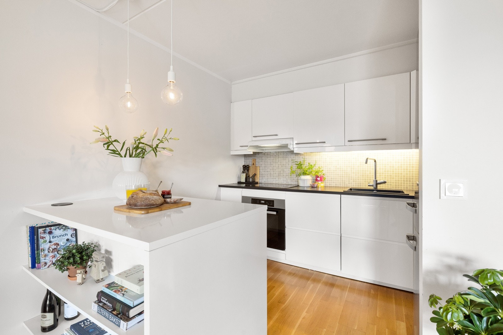 Pent kjøkken fra Ikea med integrerte hvitevarer som induksjonstopp, stekeovn og oppvaskmaskin. Galleribilde