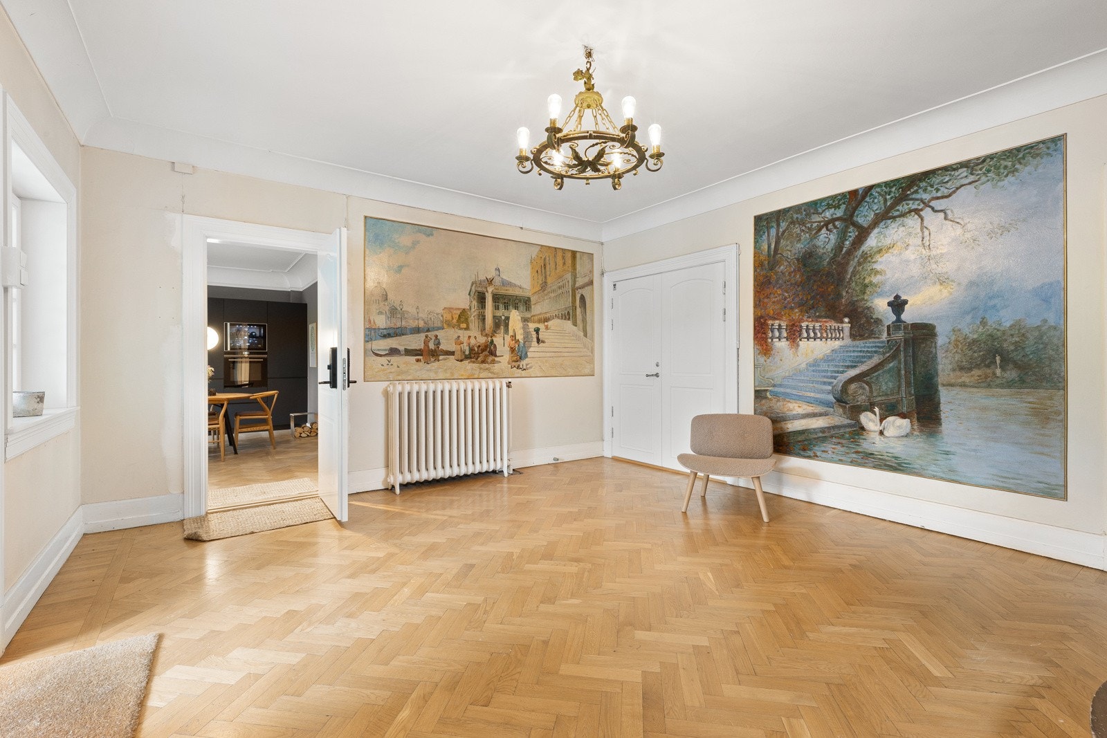 Leiligheten har et representativt felles inngangsparti med lyse farger på vegger og pen fiskebensparkett på gulv. Galleribilde