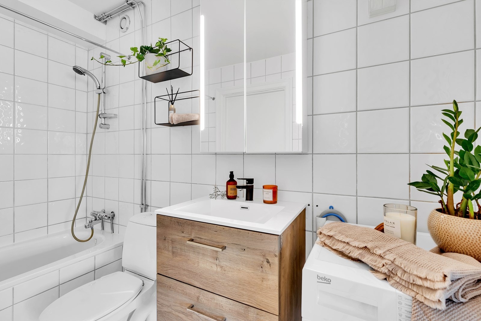 Innredningen består av servant i skuffeseksjon, speilskap, gulvmontert wc og innfliset badekar. Galleribilde