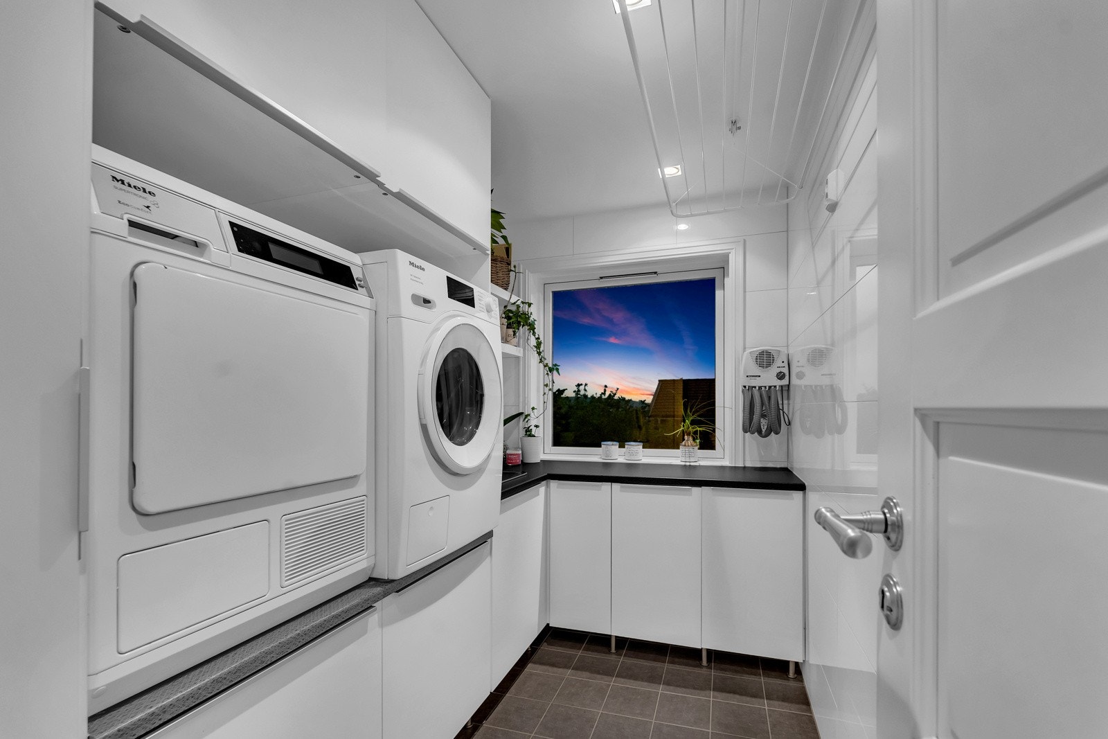 Vaskerommet har flislagte flater og innfelte spotter i himlingen. Et vindu gir supplerende arbeidslys. Det er satt inn en velutstyrt innredning med hvite, slette fronter, underskuffer, underskap og takhøye overskap Galleribilde