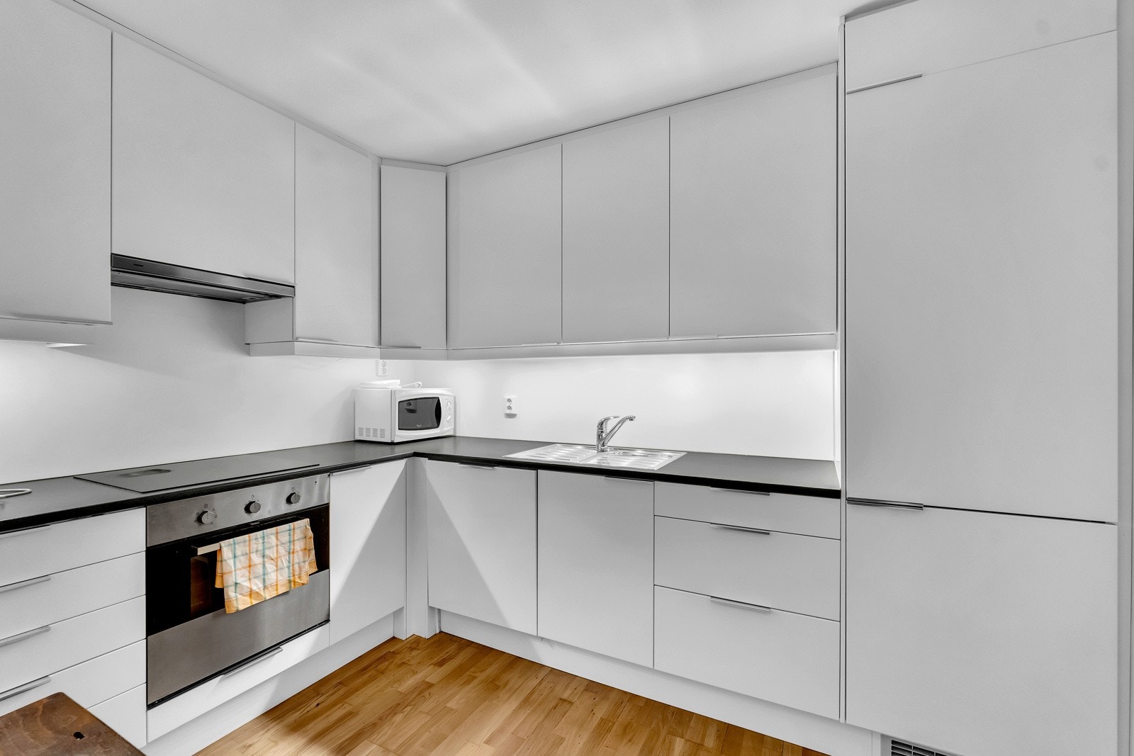 Kjøkkenet ligger i eget rom og har en velutstyrt innredning fra 2011. Den takhøye innredningen har hvite, glatte fronter, belysning, laminerte benkeplater. Integrerte hvitevarer består av stekeovn, koketopp, ventilator, oppvaskmaskin og et kjøl/frys. Galleribilde