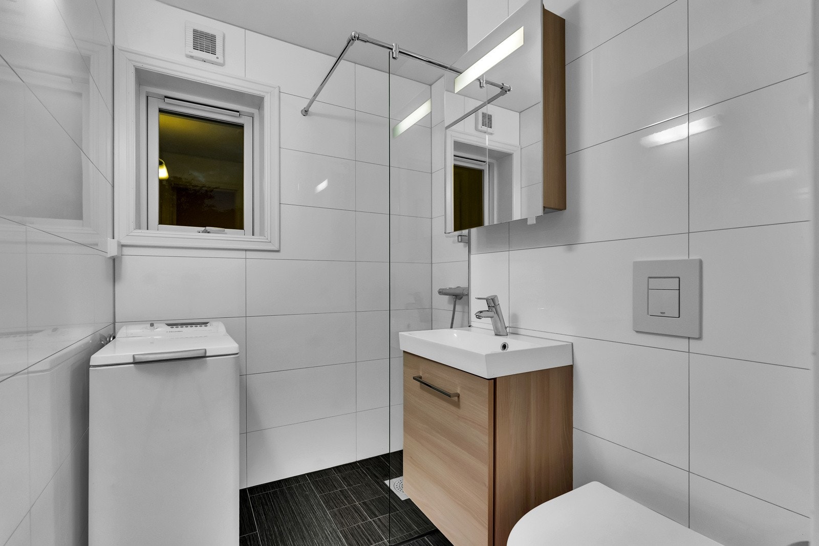 Badet ble pusset opp i 2010, og har flislagte flater, varme i gulvet og mekanisk avtrekk. Det er speilskap med integrert ledbelysning, servant på skapmøblement, vegghengt toalett og en dusjnisje med fast glassvegg. Rommet har opplegg for vaskemaskin Galleribilde