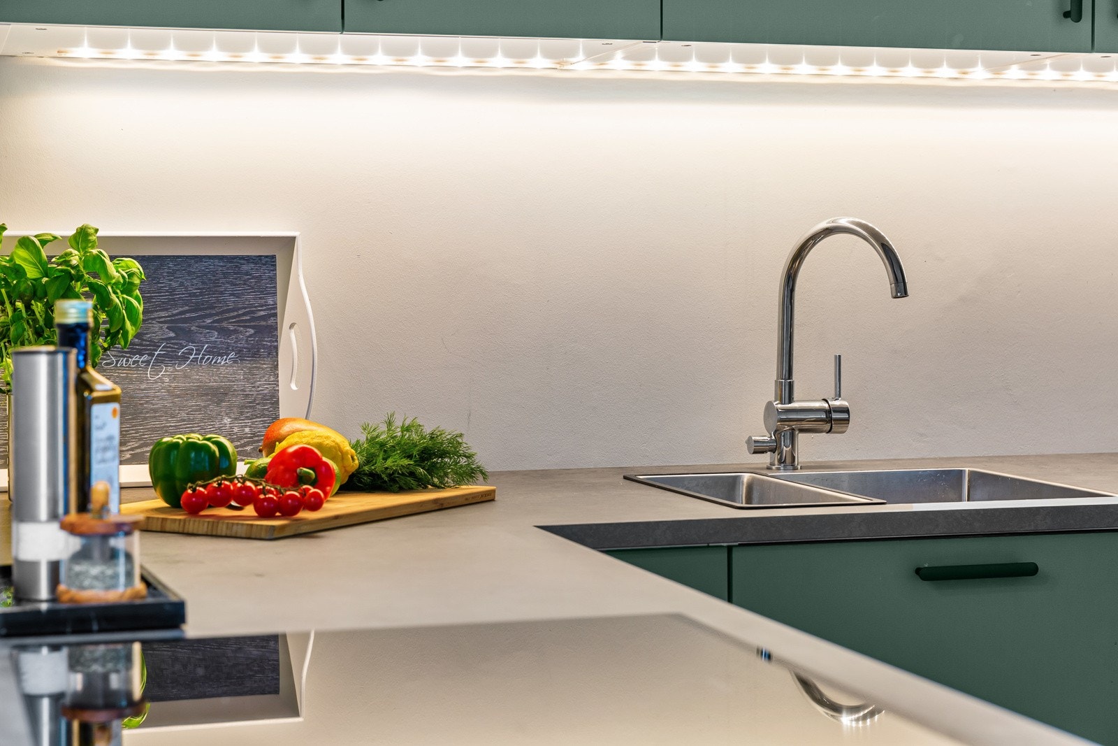 Led-stripe over benk gir fint arbeidslys. Over kokesonen henger en kullfilterventilator med glassfront. Galleribilde