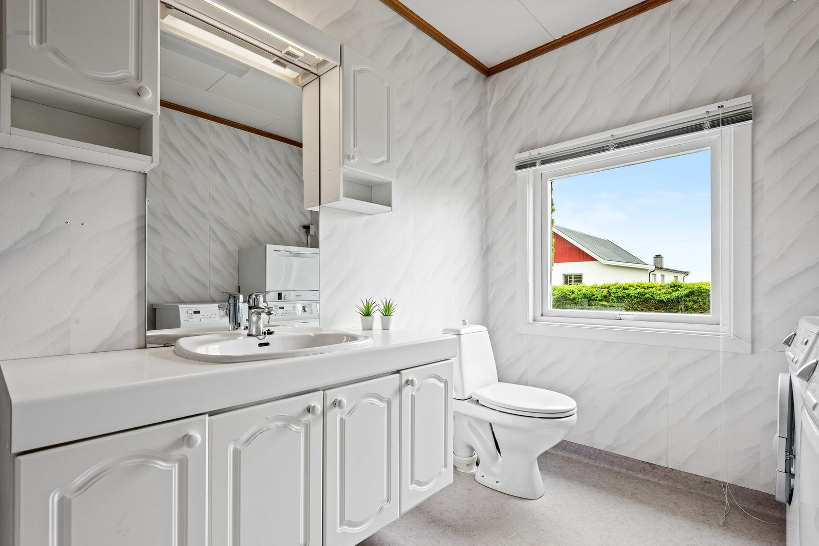 Baderommet i 1. etasje med lys spraglete våtromstapet på veggene og grått belegg på gulvet. Galleribilde