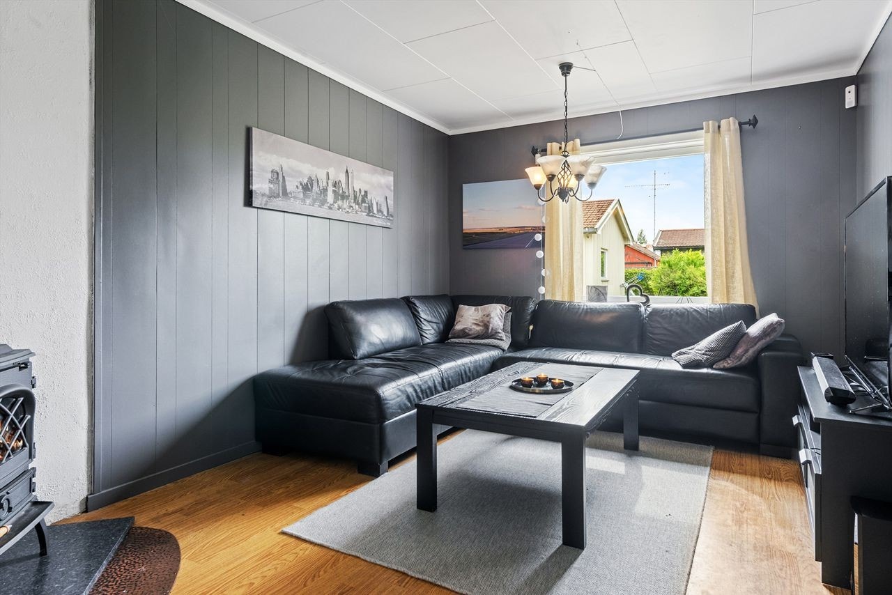 Stue med gråmalte plater på veggene og laminat på gulvet. Her kan man lage en koselig tv-krok eller bare en sofagruppe. Galleribilde