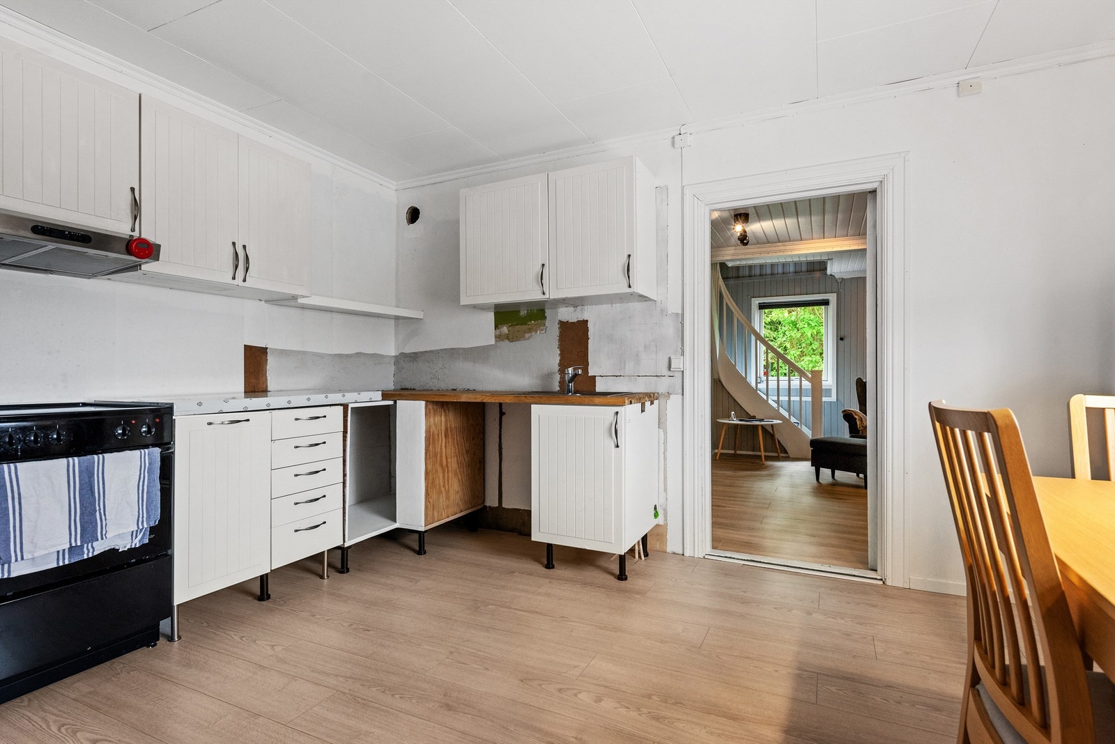 Kjøkken med lysmalte vegger og laminat på gulvet. Kjøkkeninnredning med laminerte, profilerte fronter og heltre benkeplater. Galleribilde