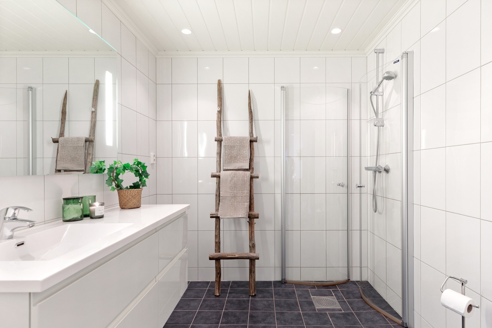 Badet har flislagte overflater, gulvvarme, downlights og dusjhjørne bak innefellbare glassdører. Galleribilde