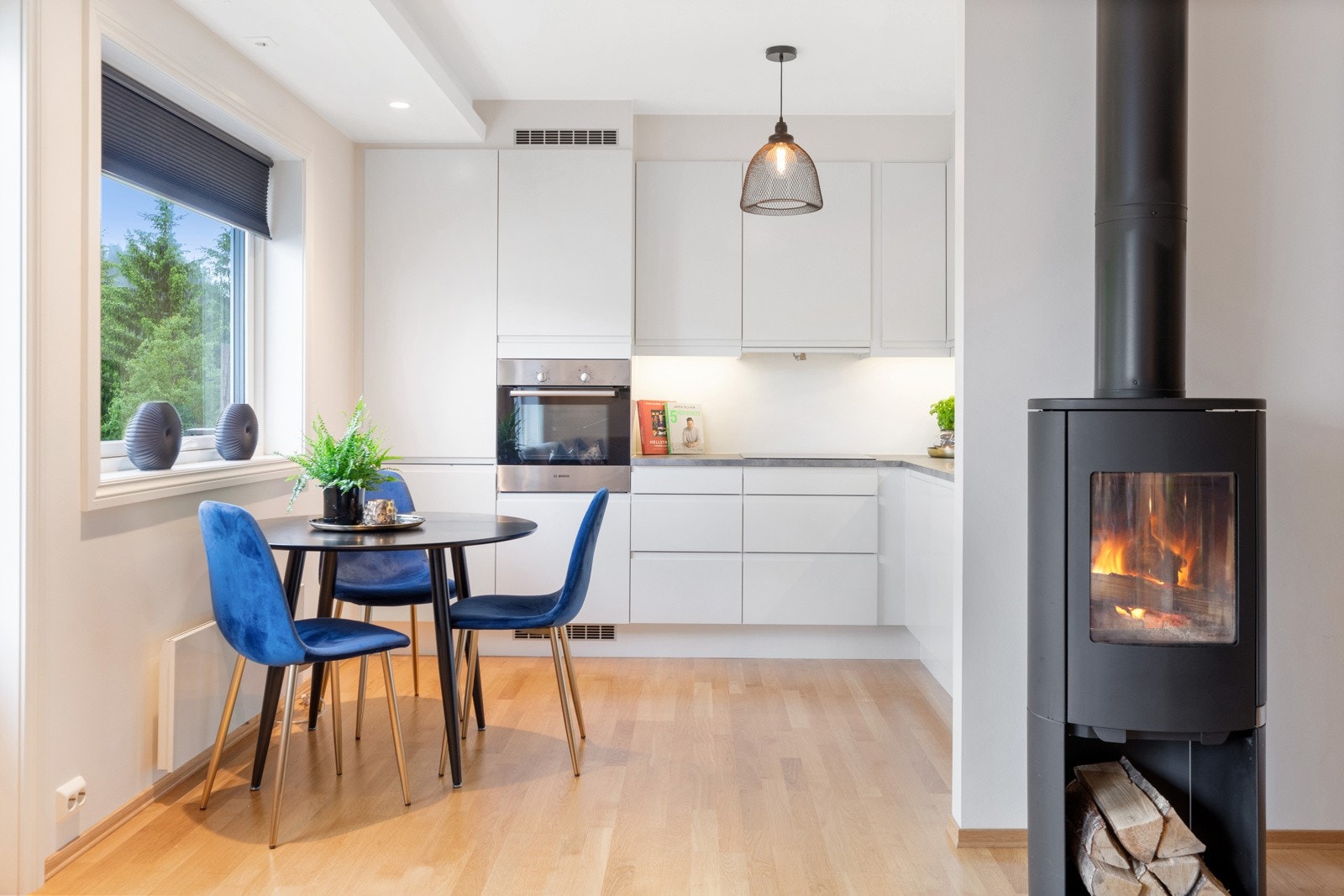 I overgangen mellom stue og kjøkken har leiligheten en moderne peisovn som gjør det varmt og koselig. Galleribilde