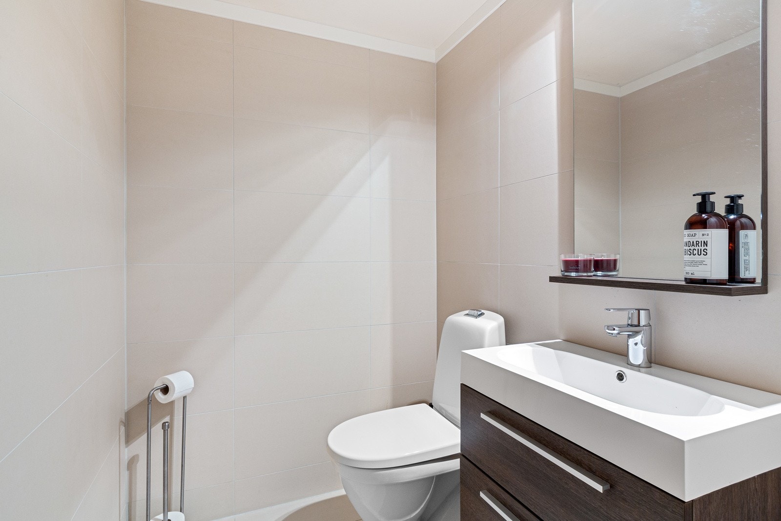 Delikat toalettrom i underetasjen med gulvstående toalett og vegghengt servantskap. Galleribilde