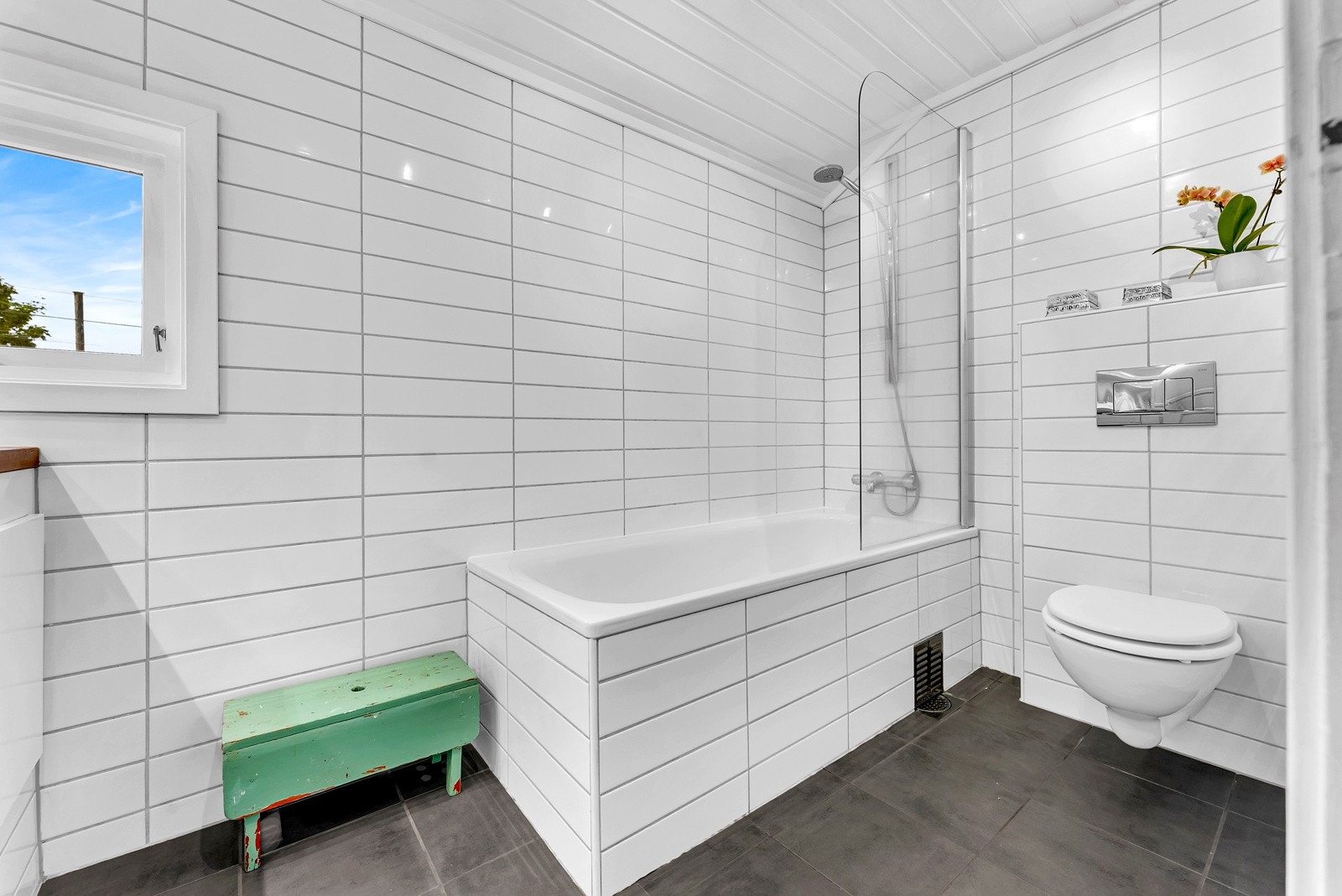 Innredningen på badet består av badekar med dusj, vegghengt toalett og servant med underskap og speil med belysning. Galleribilde
