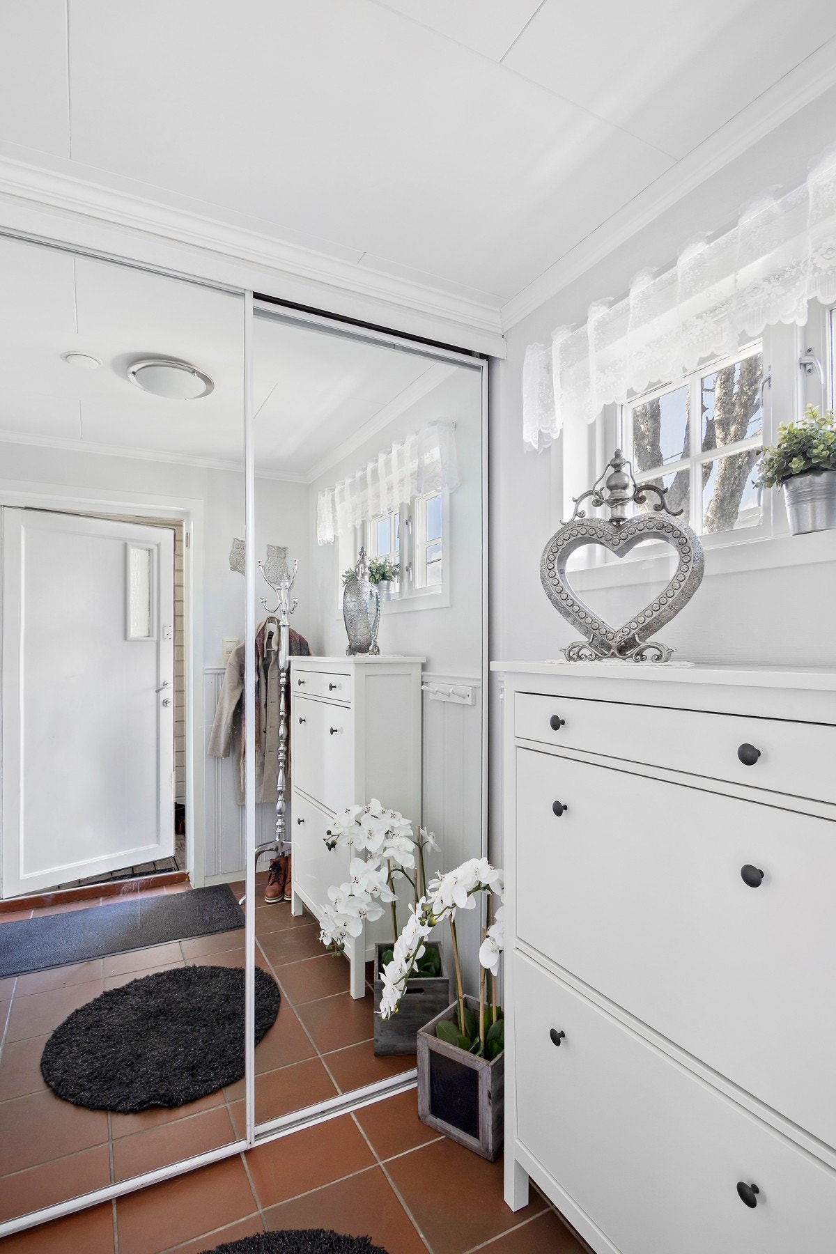 Inngangspartiet har flislagt gulv og en stor skyvedørsgarderobe med speilfronter. Galleribilde