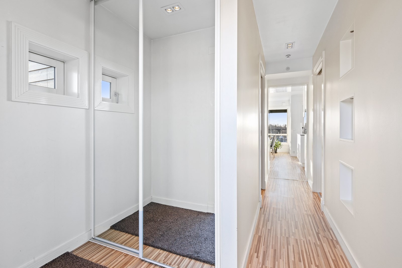 Heis opp til etasjeplan videre ut via en svalgang og inn til leiligheten. Entreen er innredet med et innebygd garderobeskap med speilfronter. Galleribilde