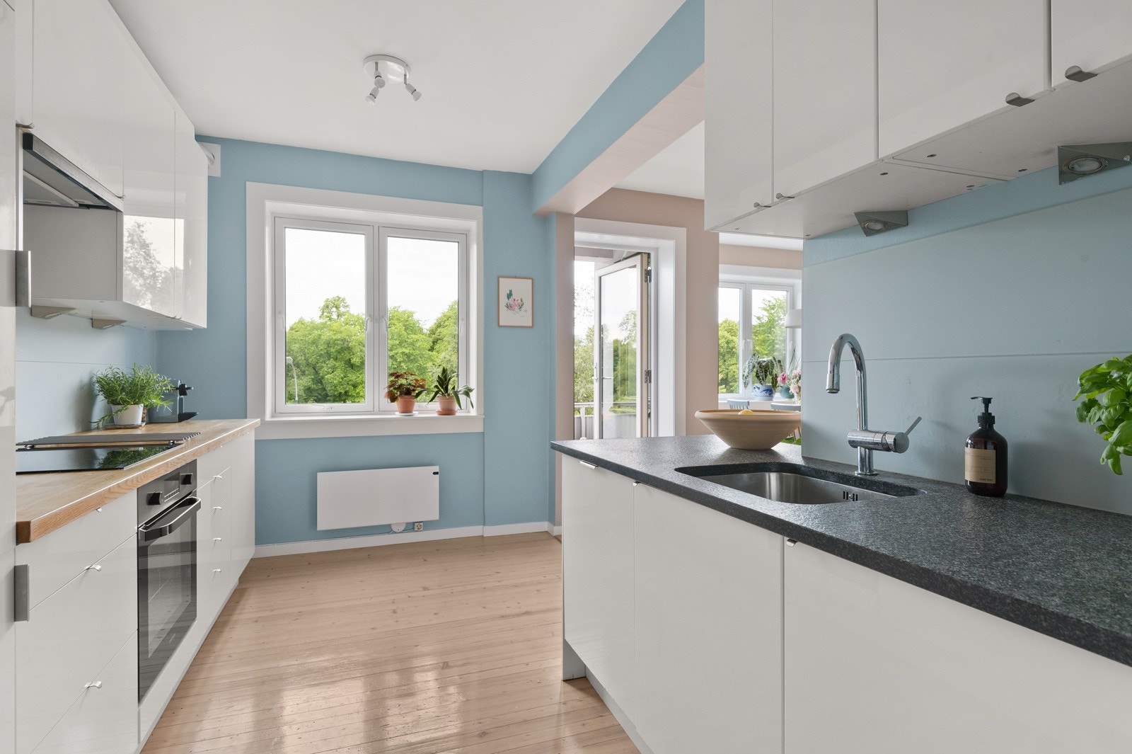 Benkeplaten av stein har underlimt oppvaskkum i rustfritt stål og armatur med uttrekkbar tut. Praktisk med glassplater i benkeryggen og belysning under overskapene. Galleribilde