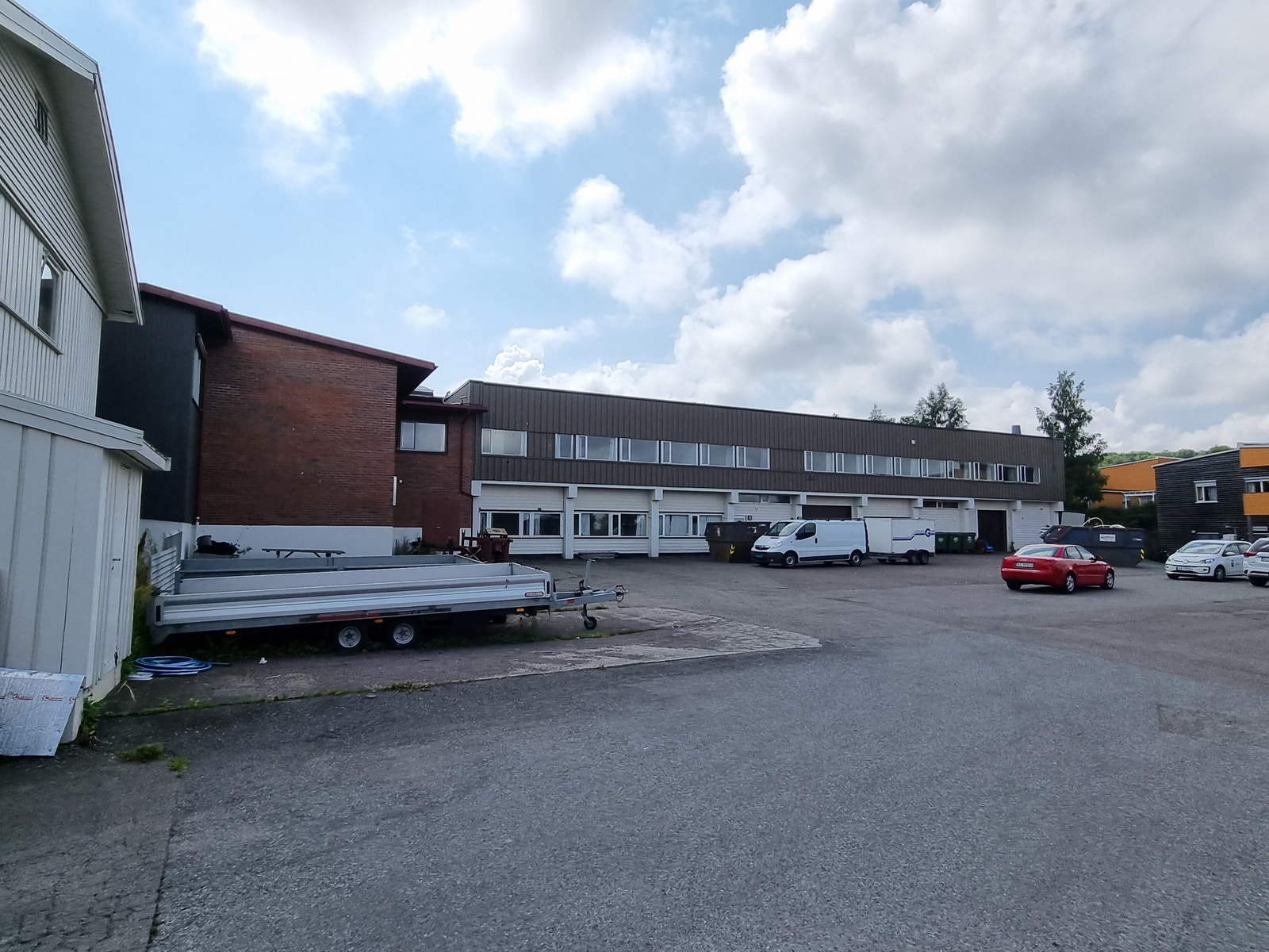 Stort næringsbygg i 2 etasjer. Flere kjøreporter på bakkeplan. Galleribilde
