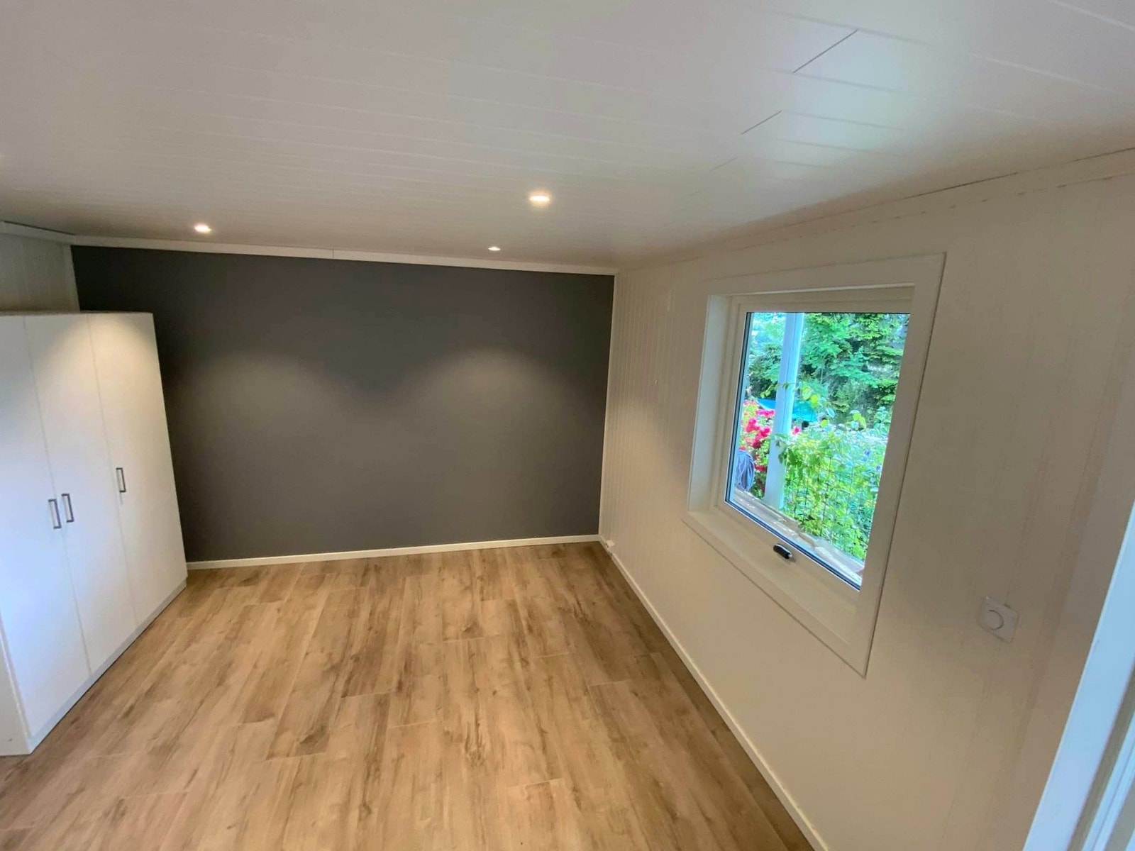 Stor rom med stor sørvendt vindu og utsikt mot hagen Galleribilde