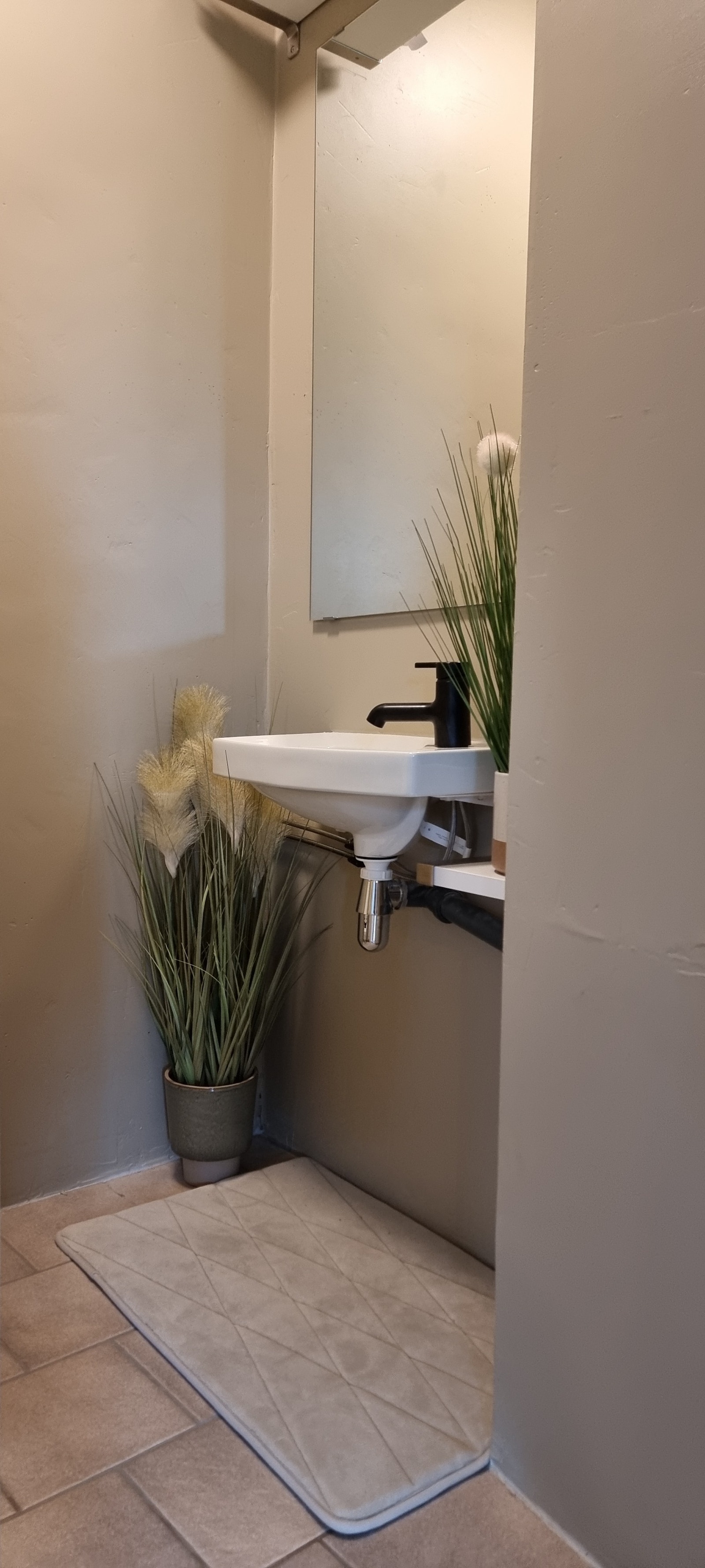Enkelt WC-rom med vask og toalett. Skap på vegg over toalett, hylle over vask for oppbevaring. Galleribilde