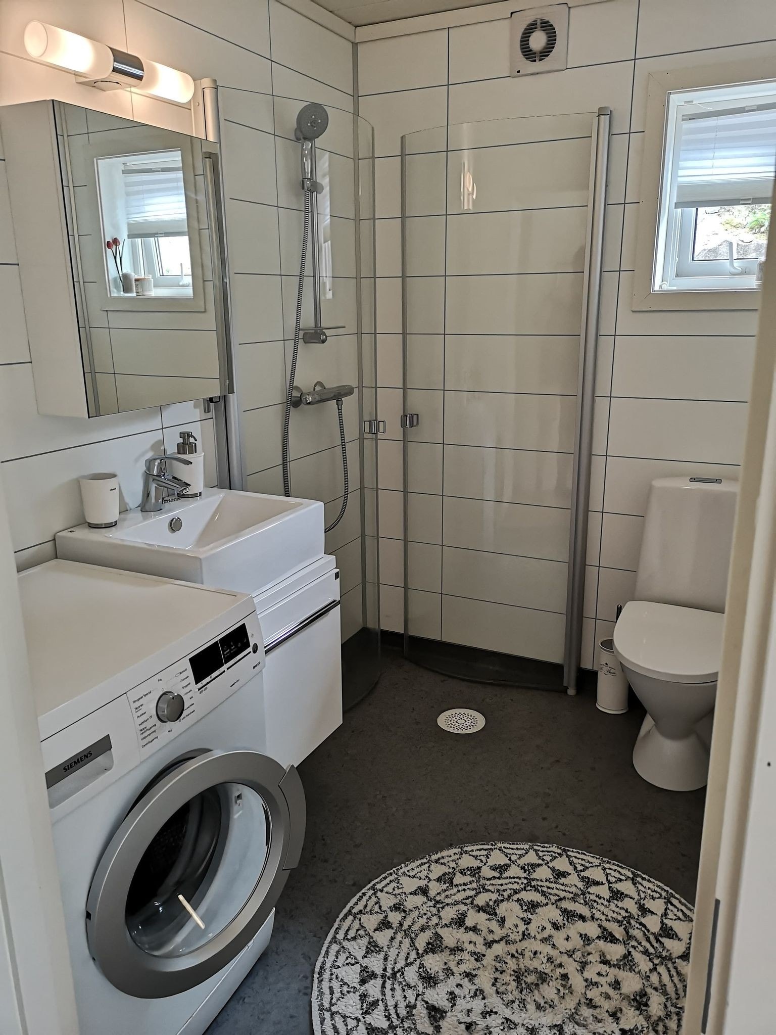 Bad med dusj, toalett og vaskemaskin. Galleribilde