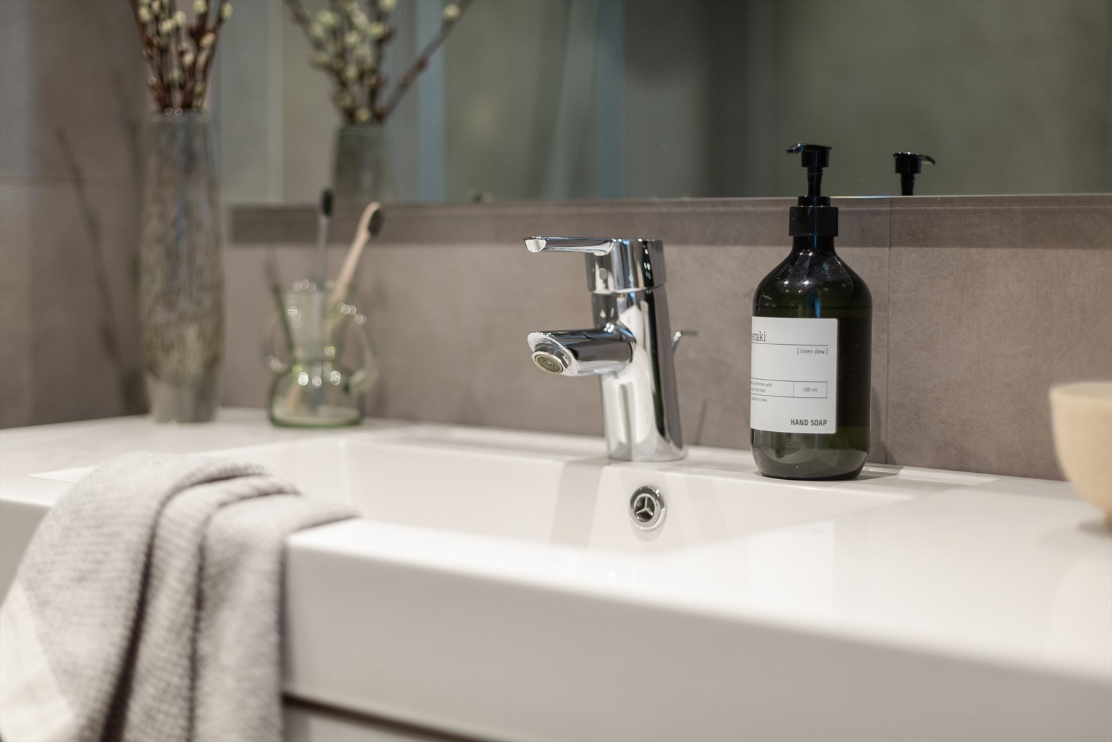 Innredning med vegghengt klosett, servantinnredning og dusj på gulv med innfellbare glassdører. Galleribilde